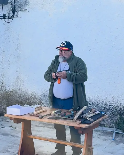 Instructor de White Neck en el taller de herramientas de corte, con cuchillos sobre una mesa de madera